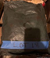 Photo of first sealed chemical warfare protective suit in original green packaging with printed model and size details.