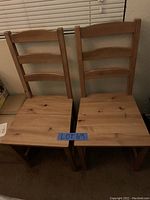 Front view of two wooden ladder back chairs with flat square wood seats.