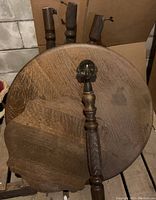View of disassembled round oak table tops with turned claw foot legs and glass ball detail on one leg.