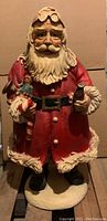 Full front view of large painted chalkware Santa Claus figure holding Coca-Cola bottle and toys.