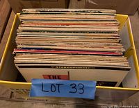 Box of vintage vinyl LP records mostly from the 1950s-1960s stored in a yellow plastic bin with a blue label reading 'LOT 33'