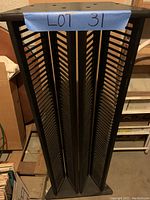 Black vertical DVD/CD media storage stand with three large compartments separated by slats, capable of holding numerous media cases. Top surface has three holes.
