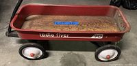 Side view of red Radio Flyer wagon showing rust inside the bed and on the edges. Wheels are white with red centers. "Radio Flyer" logo visible on the side.