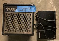 Front view of VOX amplifier showing metal grill, VOX logo, and blue tape labeled Lot 7. Sony DVD player visible to right side with power cord.