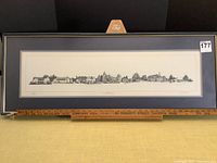 Framed panoramic black and white print of Canterbury with detailed buildings, mounted on an easel and a measuring stick below showing frame width.