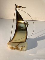 Full view of brass sailboat sculpture with mineral base showing sail, rigging, and stone base.