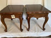 Photo showing pair of wooden Hammary side tables or benches with carved cabriole legs and scalloped edges.