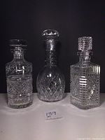 Three Irish crystal decanters with stoppers displayed side by side showing shapes and cut patterns