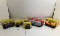 Overview of all five train cars with their original boxes: a brown passenger car, two grey boxcars, a yellow Shell tanker, and a small flatcar with a green tank.