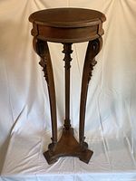 Front view of the ornate oak veneer planter table showing carved legs and round top