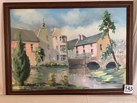 Full view of the framed oil on canvas painting showing village buildings, church with bell tower, stone bridge and water body.
