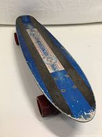 Front angle of the blue skateboard deck with Spirit of 76 sticker, showing grip tape and wear.