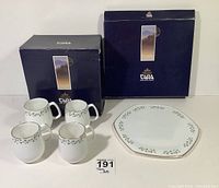Full set of four white bone china cups and one matching plate with shamrock pattern, alongside original Royal Tara boxes.