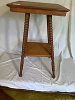 Front view of the oak side table showing the turned legs and lower shelf on a plain white backdrop.