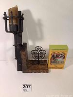 Photo of cast iron wall-mounted candle holder with brown candle, wooden bookend with metal ornament, and the boxed set of Dungeons & Dragons Endless Quest books