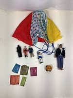 Displayed collection of vintage collectible toys including MEGO Fonzi figure, Star Wars figurines, Fisher-Price parachute figure, Barbie Little Theater tickets, and Nintendo Goomba figure, arranged on white surface.