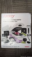 Fullstar 9 in 1 Ultimate Vegetable Chopper front of box showing the product and included attachments.