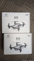 Two Deerc D20 HD Camera drones in closed factory boxes showing product image and branding.