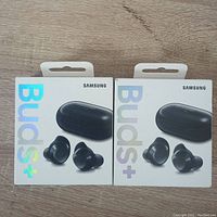 Front view of two sealed Samsung Galaxy Buds+ retail boxes showing earbuds and charging case image