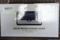 Boxes of solar motion sensor lights with label and image of the product on the box, showing product features and packaging.