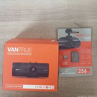 Photo shows two items: Vantrue OnDash N2 PRO dashcam in orange-and-white box and Vantrue CycleHigh 256GB MicroSDXC memory card in sealed packaging.