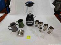 Photo showing Black & Decker blender, ceramic mugs, stainless steel wine glasses, clear glass shot glasses, and stainless steel flask.