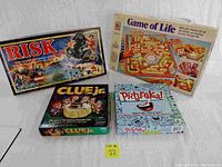 Four boxed board games: Risk, Clue Jr., Game of Life, Pictureka, arranged closely on a flat surface.