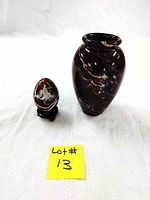 Photo showing the burgundy marble vase and stone egg on wooden stand side by side on white background with lot number.