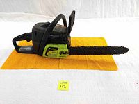 Full view of the Poulan chainsaw laid flat on yellow towel showing the entire tool including handle, body, and chain bar.