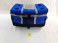 Photo of blue collapsible cooler with wheels and handles, showing top with four cup holders and slight dirt marks.