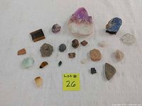 Photo of all 22 stones and crystals including different varieties against white fabric background with lot number card.