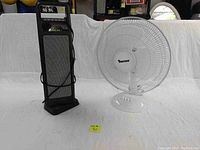 Overview photo showing both the white Tooltech area fan and the black ceramic tower heater side by side on a white cloth backdrop.
