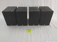 Four JBL small box speakers front view showing black mesh covers and JBL logos.