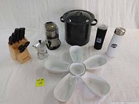 Full lot view showing knife block, espresso maker, coffee grinder, pot, water bottles and serving dishes arranged on white background.