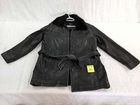 Full front view of men's black leather long coat laid flat showing fur collar and attached waist belt.