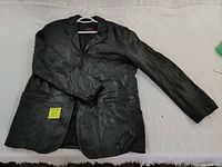 Black leather men's jacket laid out flat to show front and sleeves.