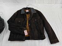 Photo showing the front of a dark brown suede leather men's jacket with a plaid inner lining and button-down front, missing two buttons.