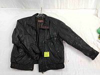 Front view of the black leather jacket laid flat, showing zip-up front, collar, and pockets.