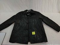Full front view of large black leather jacket laid flat on white surface showing design and condition.