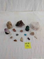 Overview of all 17 stones and crystals laid out on a white cloth including quartz, amethyst, metamorphic rocks, malachite egg, wooden stand, plastic stand, and miscellaneous stones.