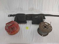 Photo showing the Eagle safety can, large black Husky tool belt with metal buckle and pockets, and a coil of galvanized cable on metal spool