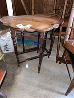 Front view of the antique wooden gate leg table showing scalloped edges on drop leaves and turned legs.