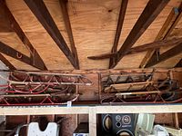 Overview of six antique sleds stacked in a garage storage area showing wood slats and metal frames.