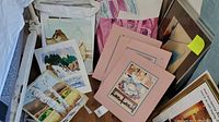 Overview of assorted watercolor paintings and drawings on floor with some framed pieces leaning against wall