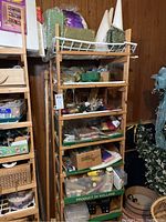 View of wooden shelving filled with various boxes and small craft items including foam forms, holiday accents, tissue paper, and glass stones.