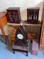 Overview of various wooden items including jewelry boxes, wooden crates, a decorative panel, footstool, and one clock on a footstool.