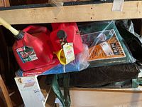 Tarps stacked with two red plastic gas cans on top, showing detailed gas can caps and tarp colors