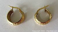Top view of the pair of small hoop earrings showing the diamond cut embossed pattern on the outer surface.