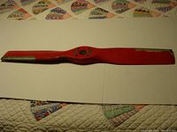 Full view of the entire red wooden airplane propeller showing shape and length.