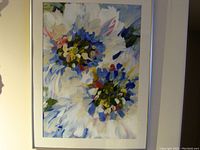Framed watercolor painting hung on wall showing abstract floral design with blues, whites, greens, and colorful accents.